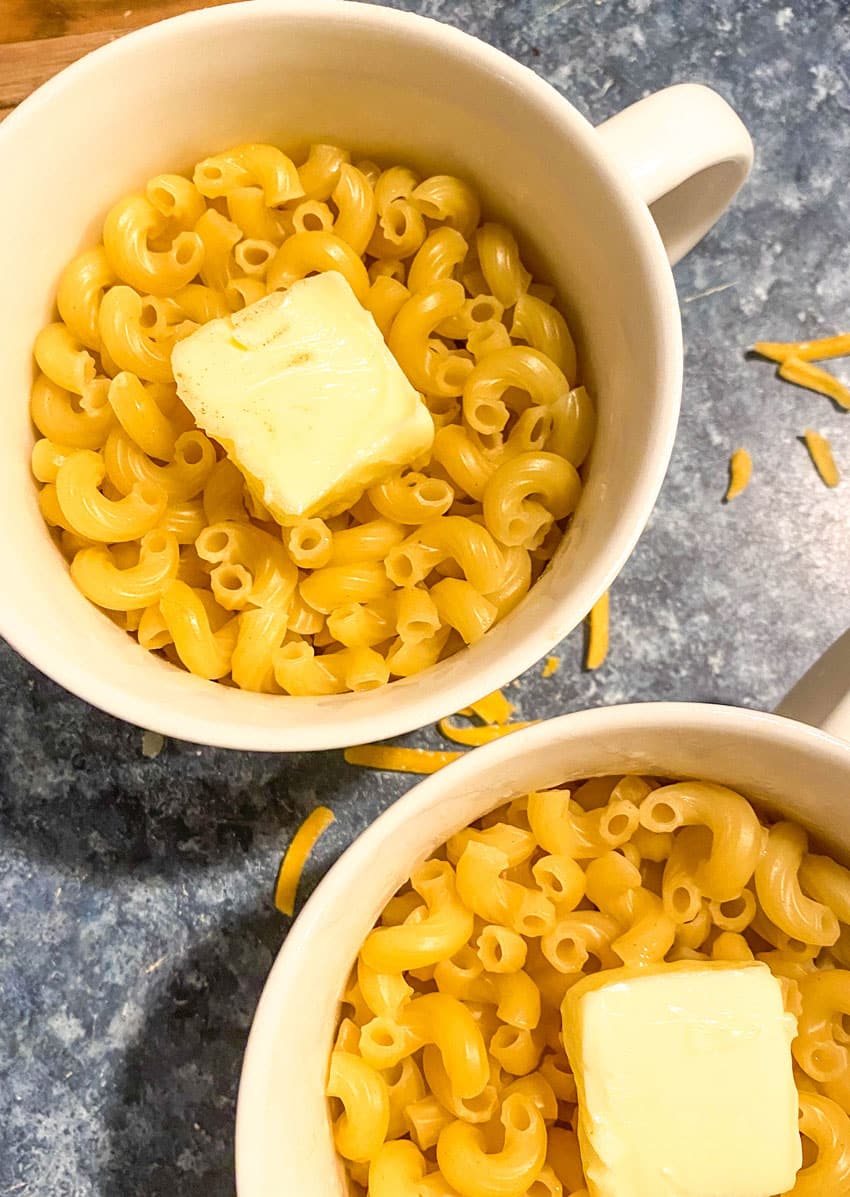 two mugs filled with pasta and pats of butter