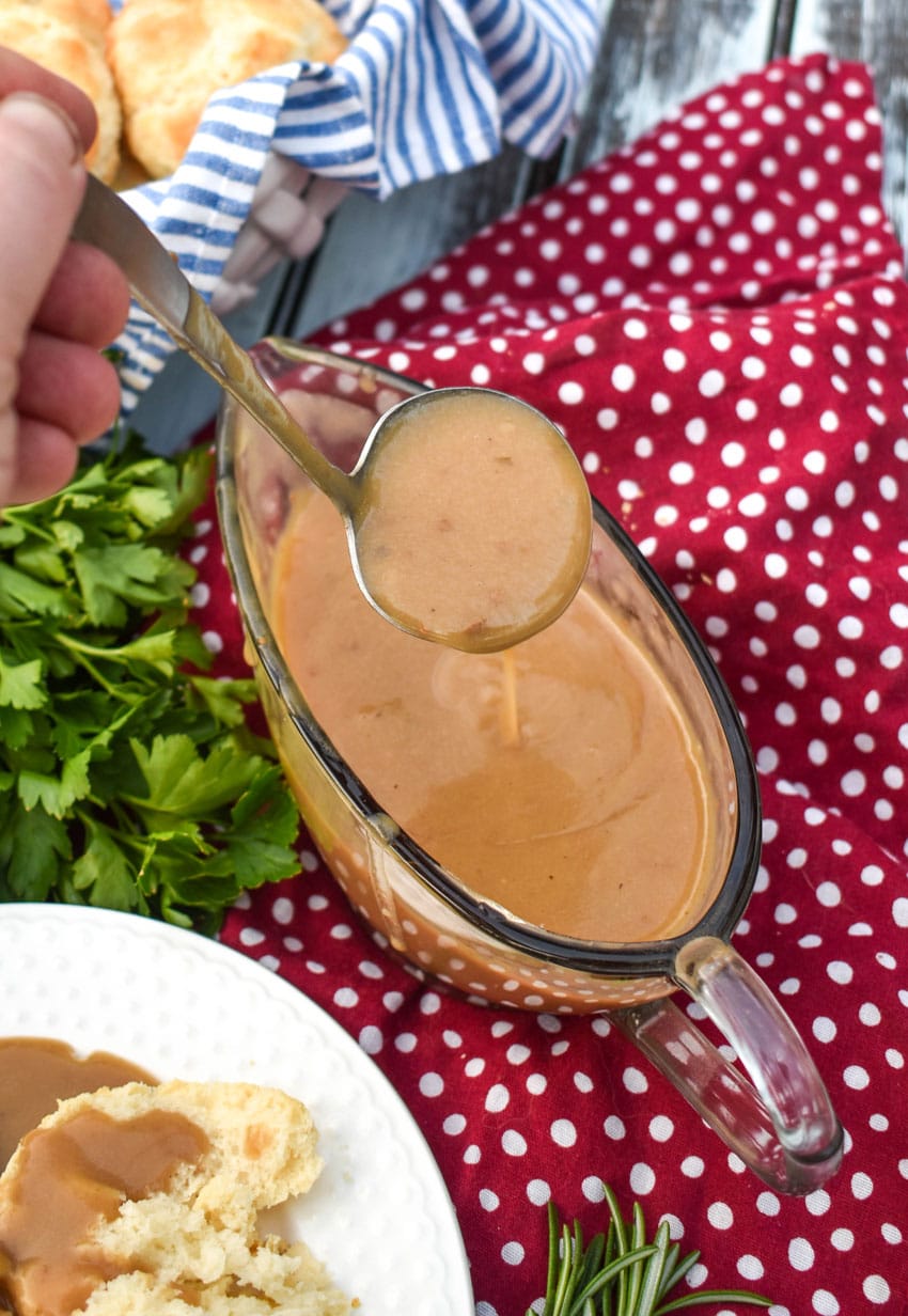 rich, dark easy homemade turkey gravy being ladled out of a glass gravy boat