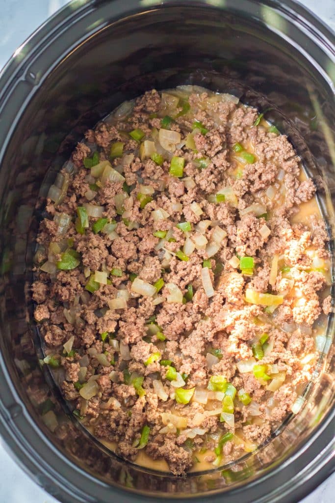 sauteed ground beef with peppers and onions in the black bowl of a crockpot