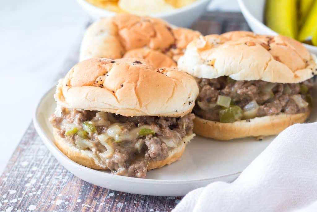 slow cooker philly cheesesteak sloppy joe sandwiches arranged on a white plate