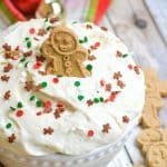 a gingerbread cookie stuck in a bowl of fluffy sugar cookie dip
