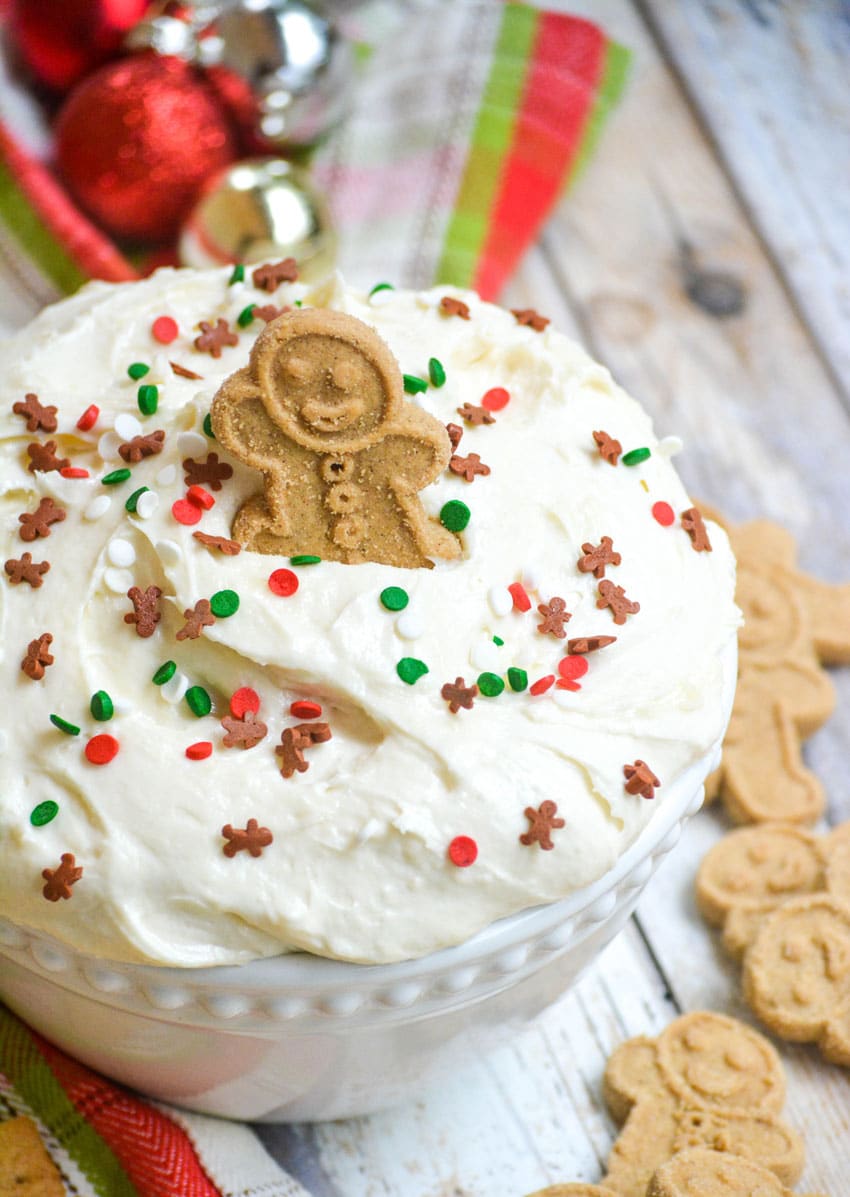 a gingerbread cookie stuck in a bowl of fluffy sugar cookie dip