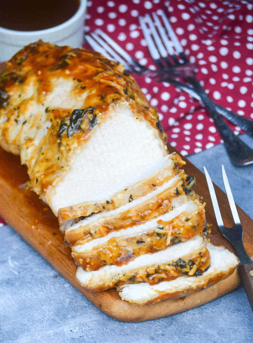 a meat fork stuck in slices of honey garlic pork tenderloin on a wooden cutting board