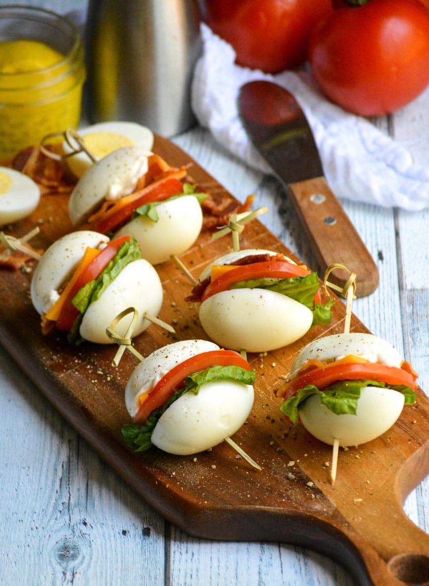 hard boiled egg blt bites arranged on a narrow wooden cutting board