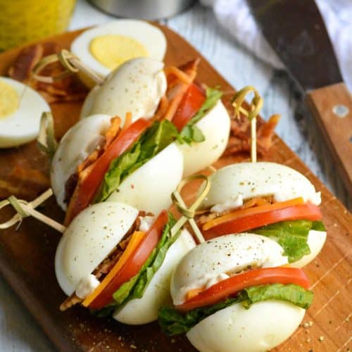 hard boiled egg blt bites arranged on a narrow wooden cutting board