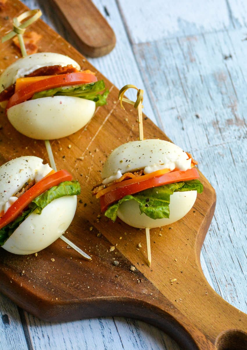 hard boiled egg blt bites arranged on a narrow wooden cutting board