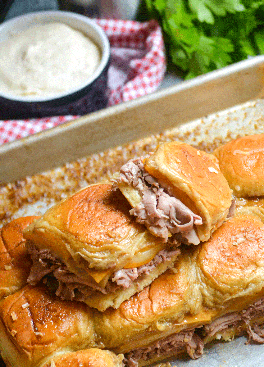 roast beef and cheddar sliders with horseradish sauce on a metal baking sheet