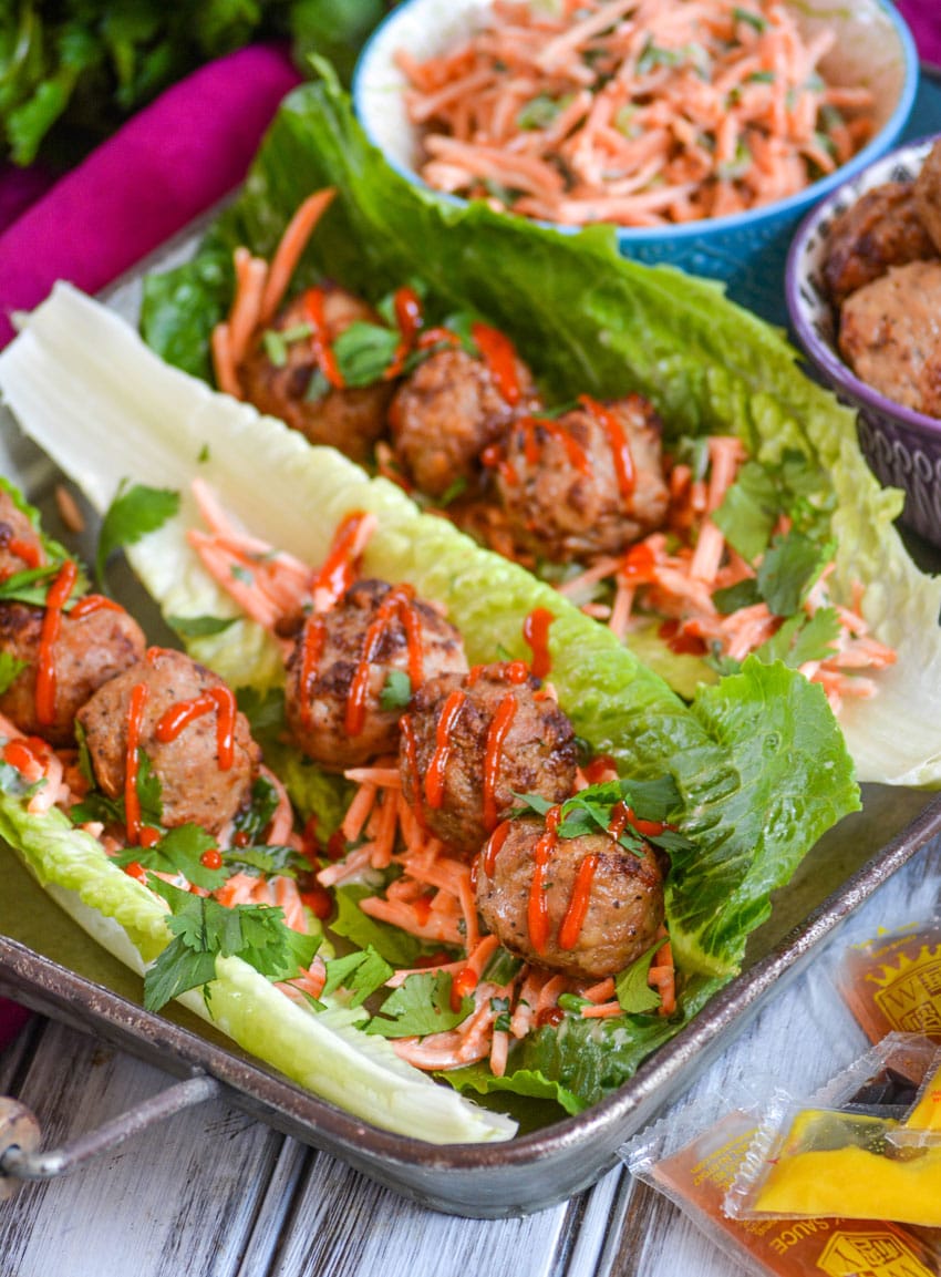 teriyaki meatball lettuce wraps drizzled with sriracha sauce on a silver tray