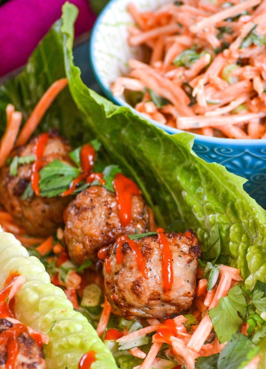 teriyaki meatball lettuce wraps drizzled with sriracha sauce on a silver tray
