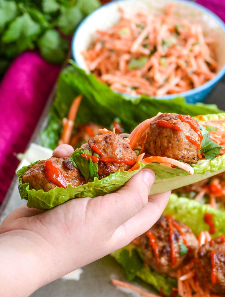 a hand holding up an asian style teriyaki meatball lettuce wrap