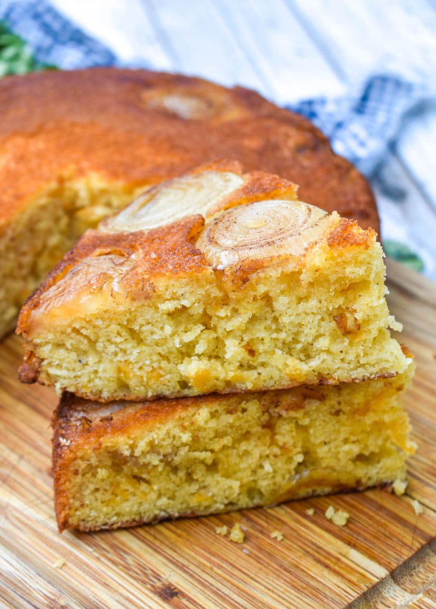 a stack of caramelized onion topped cornbread on a wooden cutting board