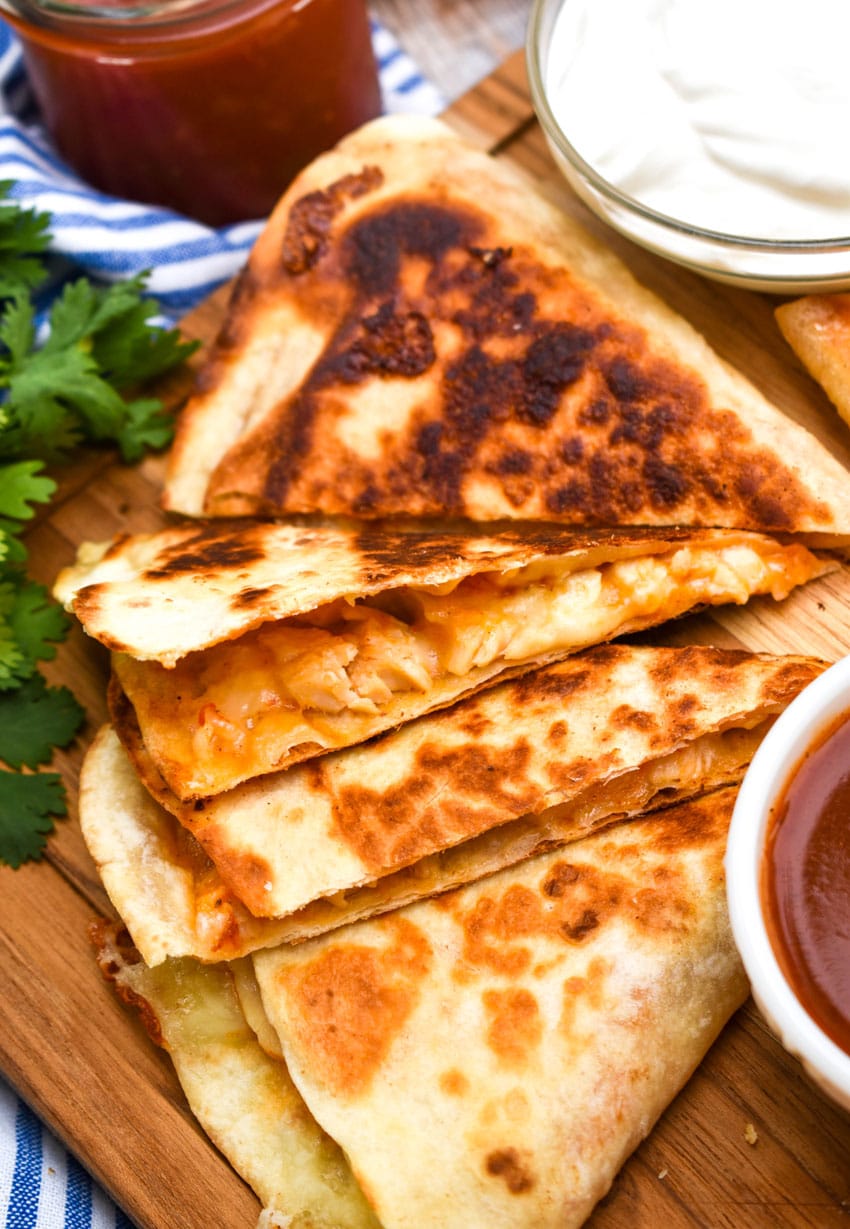copycat taco bell cheesy chicken quesadillas on a wooden cutting board