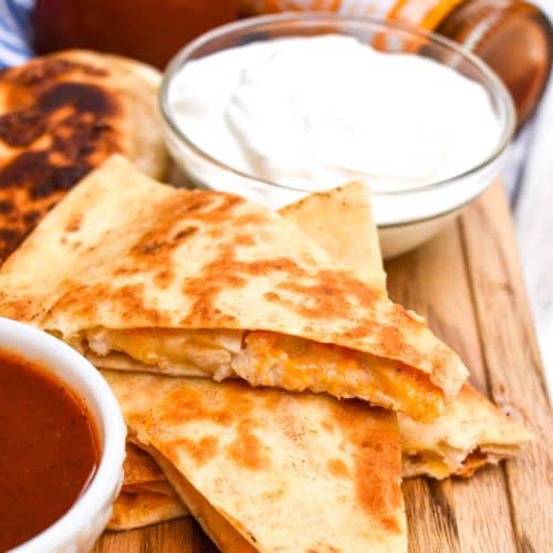 copycat taco bell cheesy chicken quesadillas on a wooden cutting board