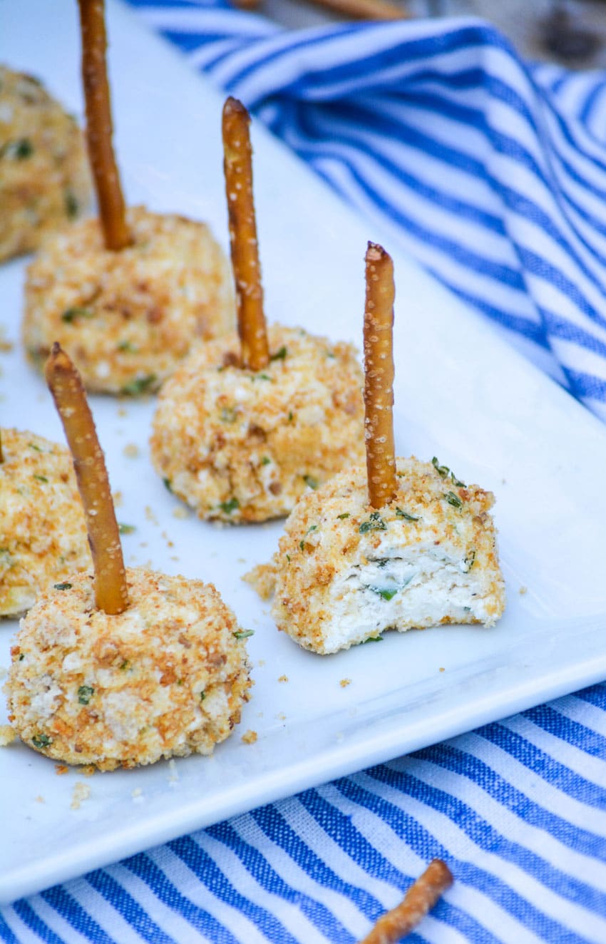 miniature cheese balls made with goat cheese arranged in two rows on a white platter