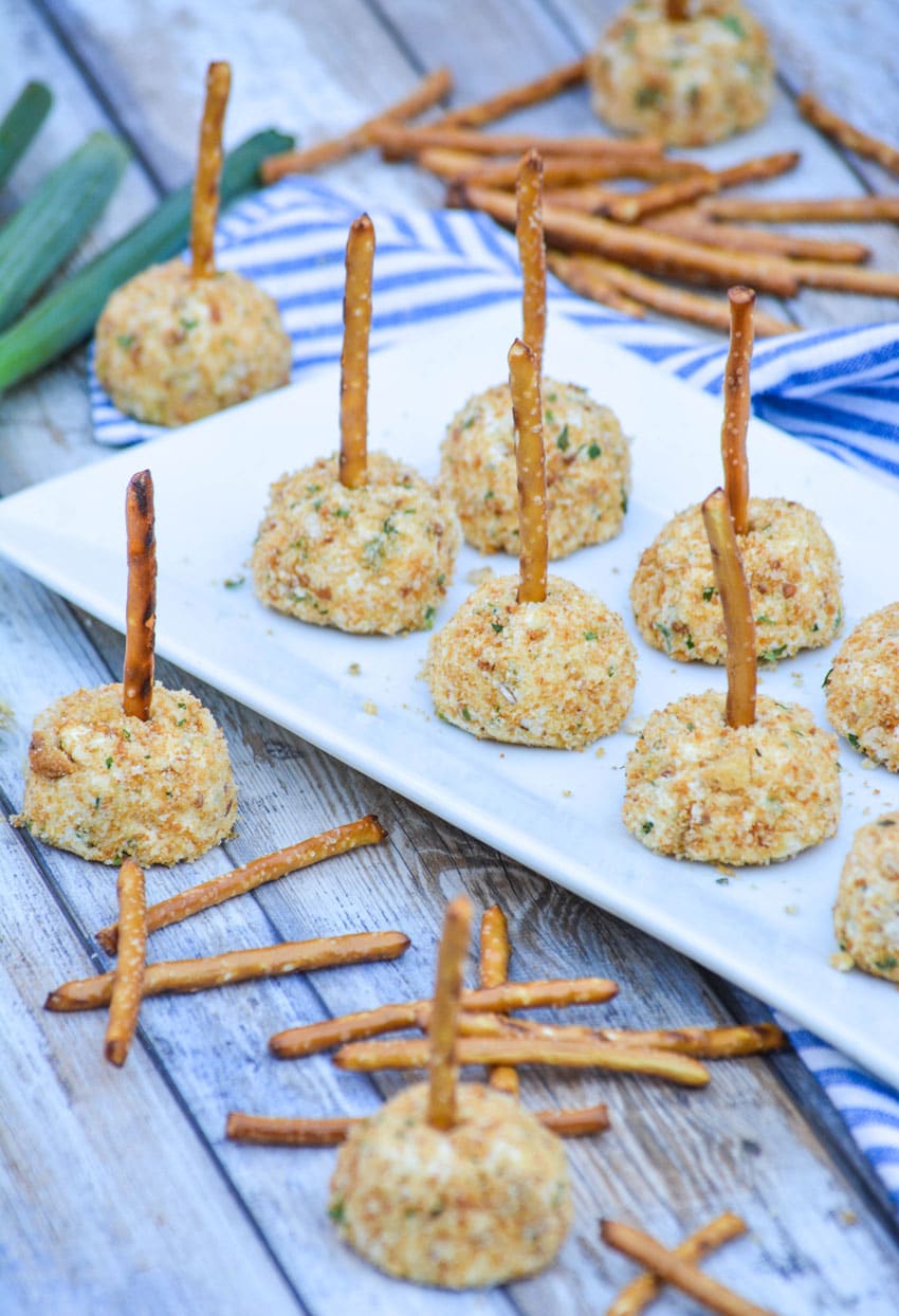 miniature cheese balls made with goat cheese arranged in two rows on a white platter
