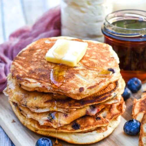 a stack of muffin mix pancakes on a wooden cutting board topped with a pat of butter and syrup