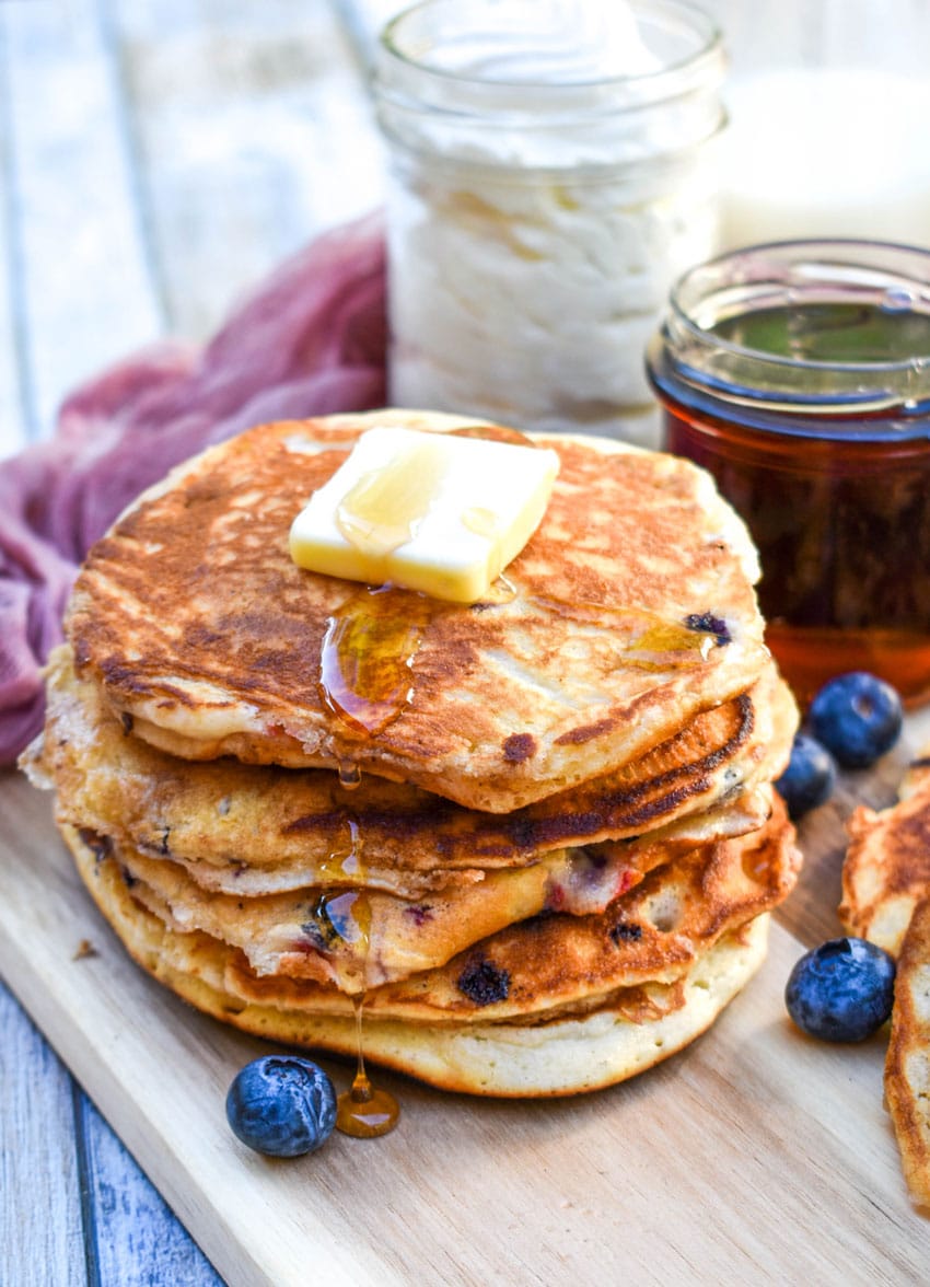 a stack of muffin mix pancakes on a wooden cutting board topped with a pat of butter and syrup