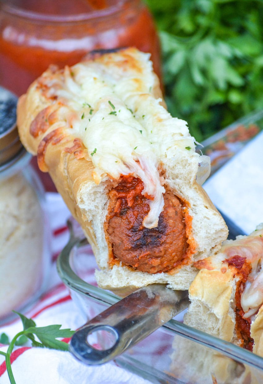 quick and easy meatball sub sandwich resting on the corner of a glass baking dish