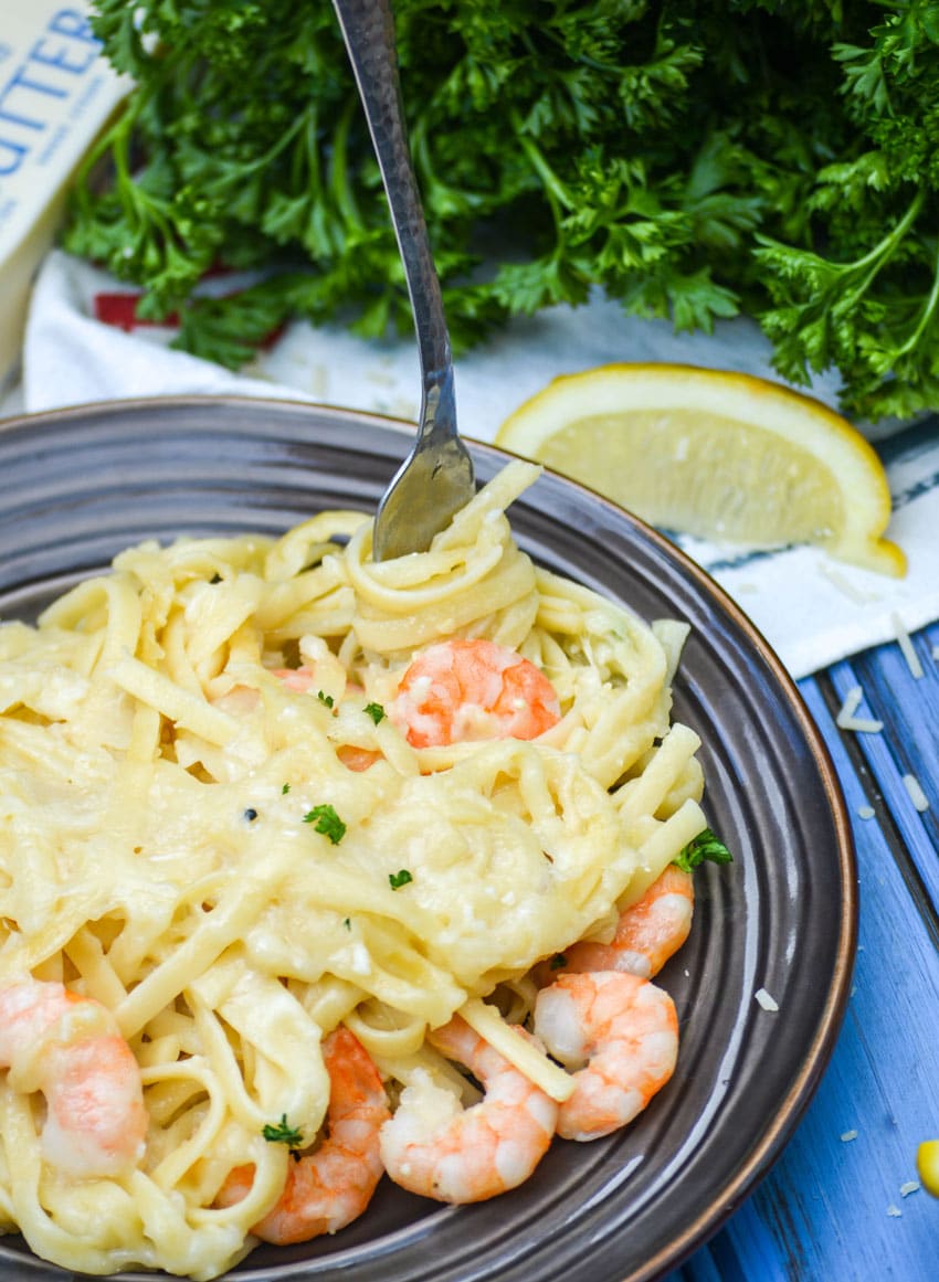 a silver fork digging into baked shrimp scampi casserole on a small brown plate