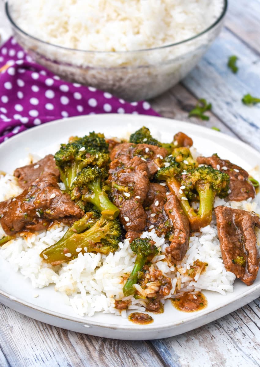 crockpot beef and broccoli over steamed white rice on a white plate