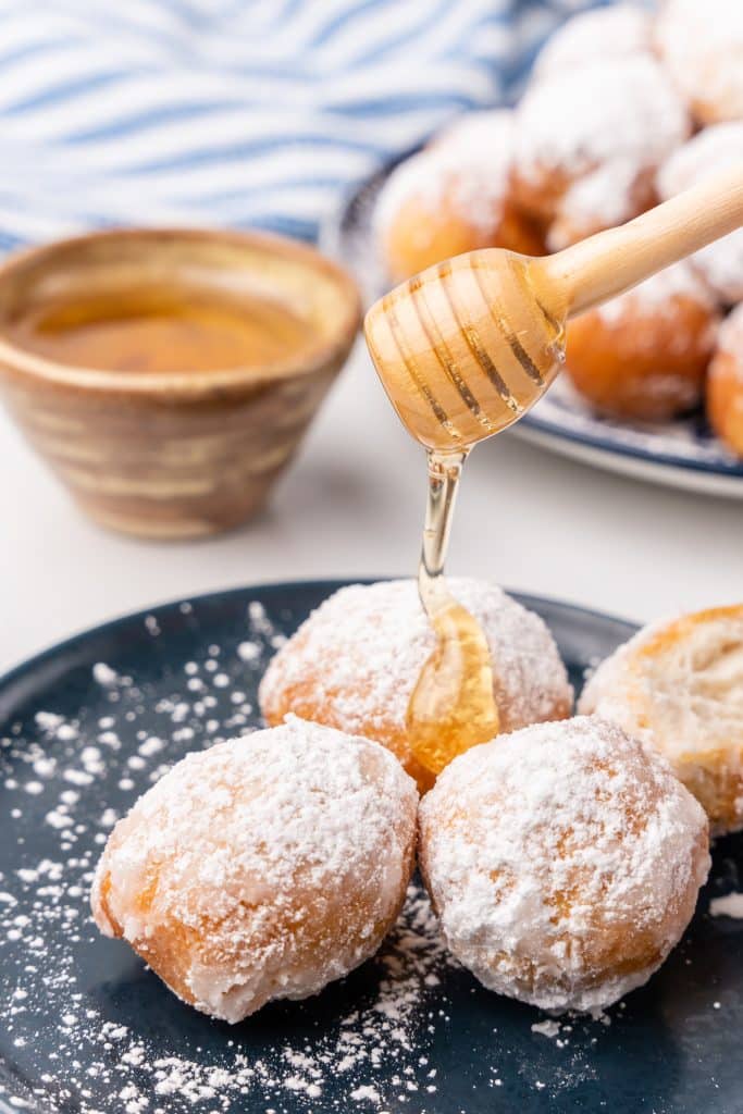 honey being drizzle over a plate of easy homemade beignets