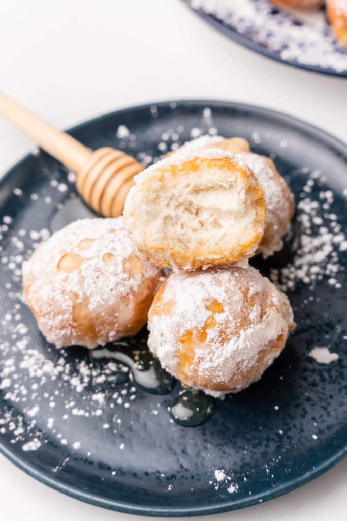 honey covered beignets on a blue plate