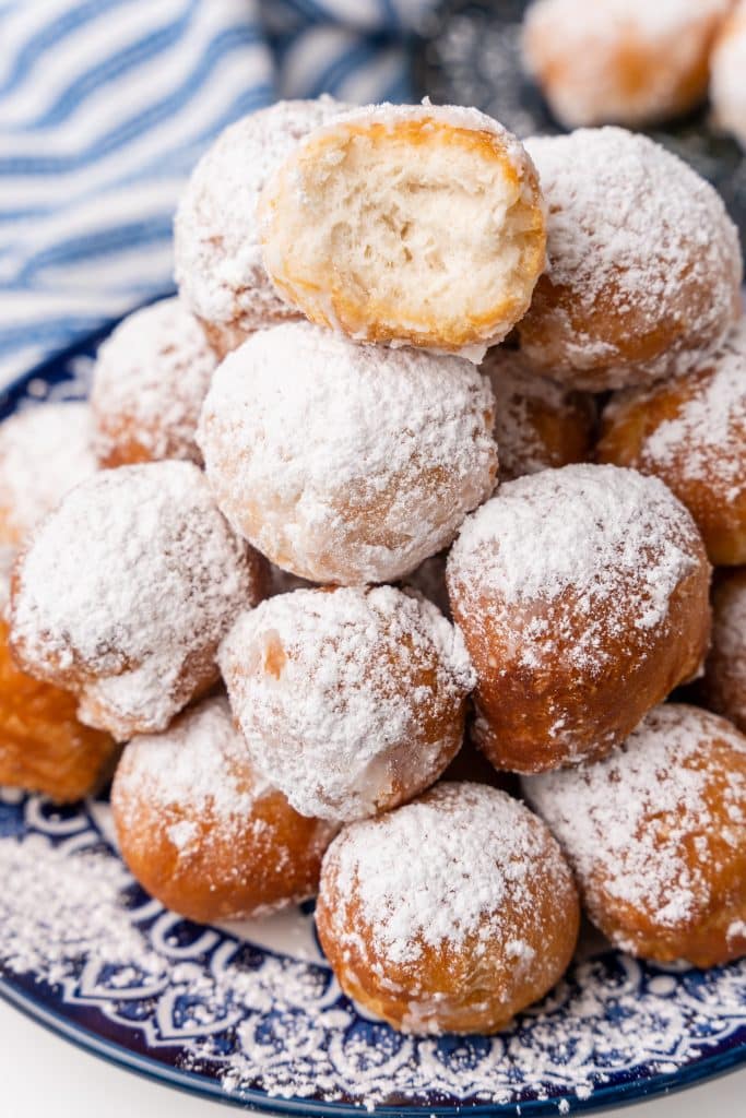 canned biscuit beignets piled on a blue and white plate