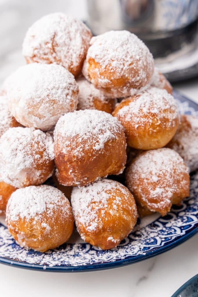 canned biscuit beignets piled on a blue and white plate