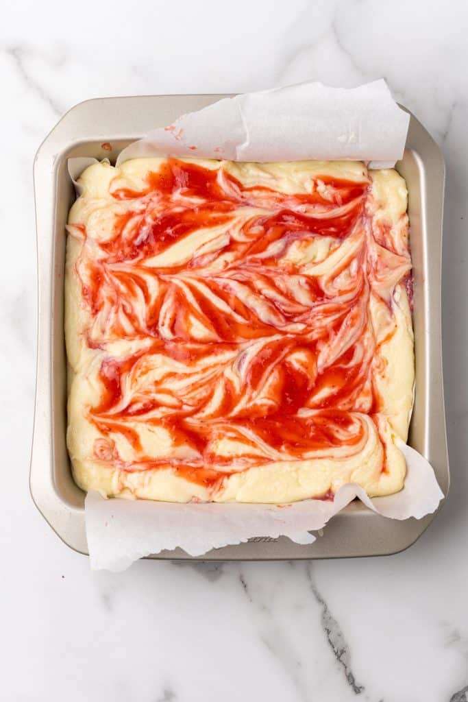 strawberry swirled white chocolate fudge in a parchment paper lined baking dish