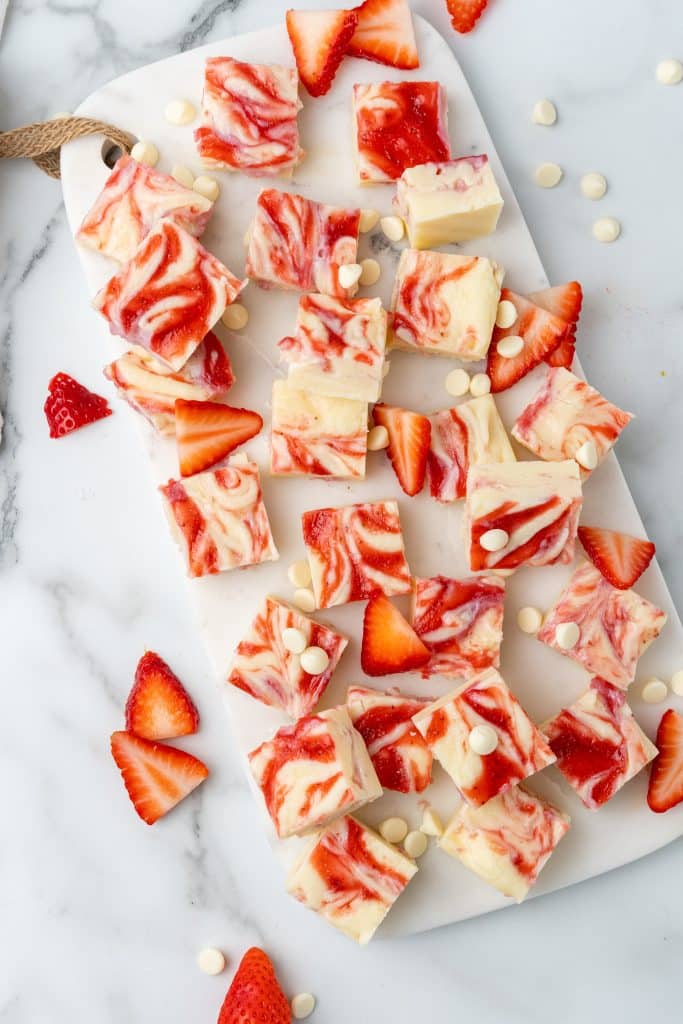 squares of strawberry and cream fudge on a white cutting board