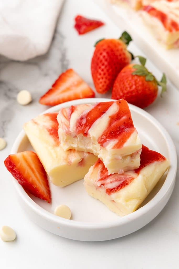 squares of strawberry and cream fudge on a white cutting board