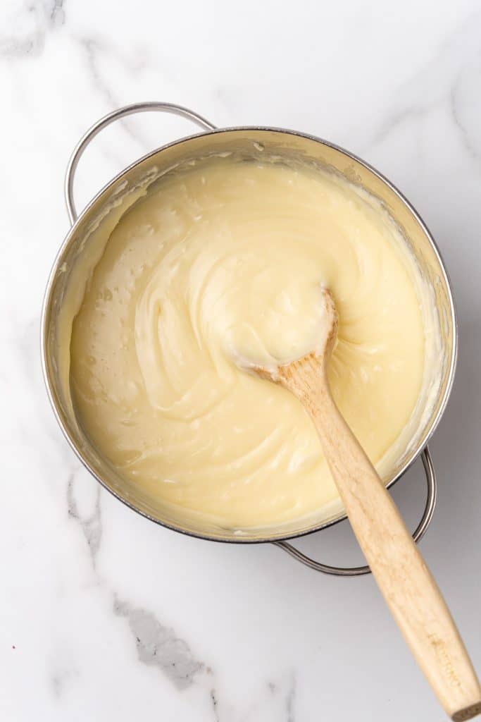 melted white chocolate and a wooden spoon in a large silver pot
