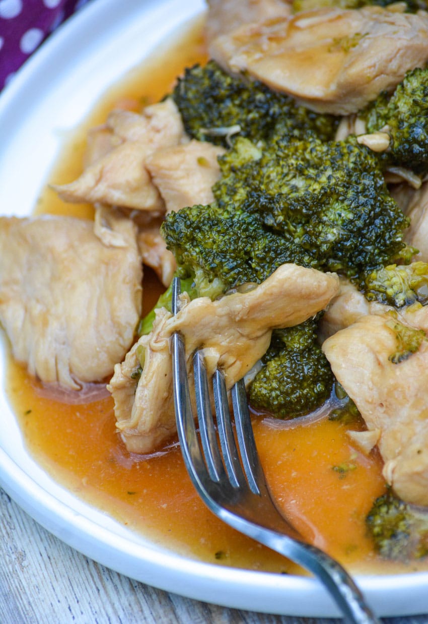 a fork resting on a white plate filled with instant pot chinese chicken and broccoli