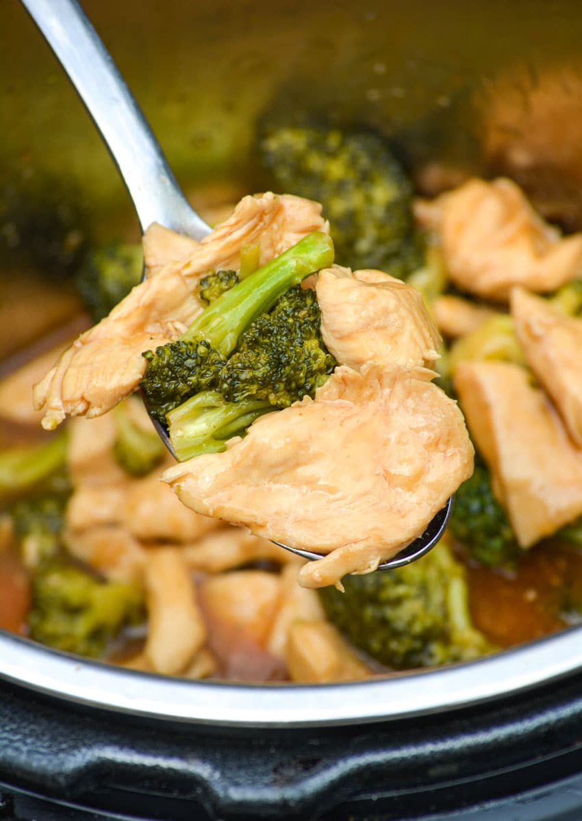 a silver spoon holding up a scoop of chinese chicken and broccoli above the bowl of an instant pot