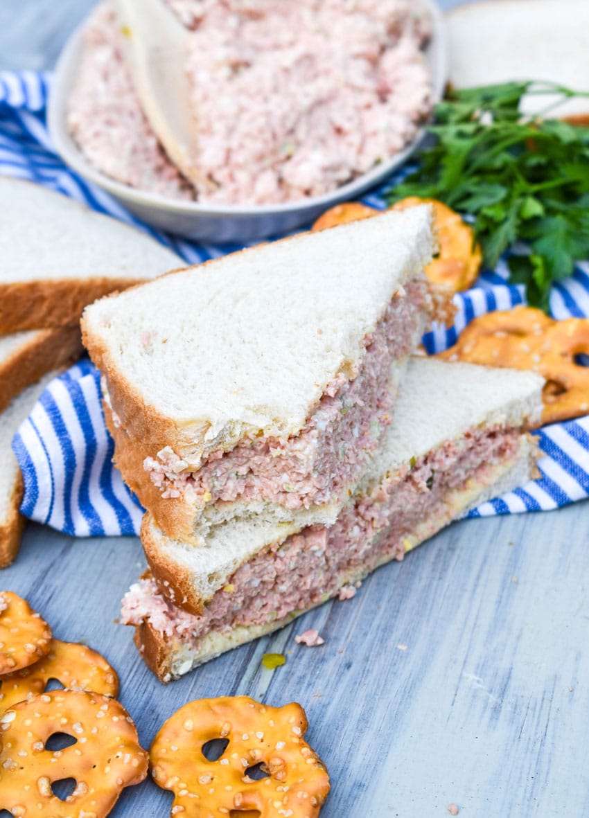 two halves of a bologna salad sandwich on a wooden table