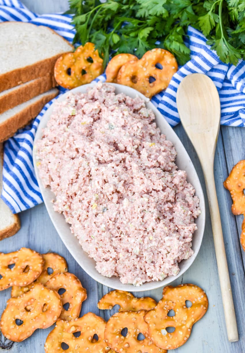 old fashioned bologna salad in a white dish with a wooden spoon on the side
