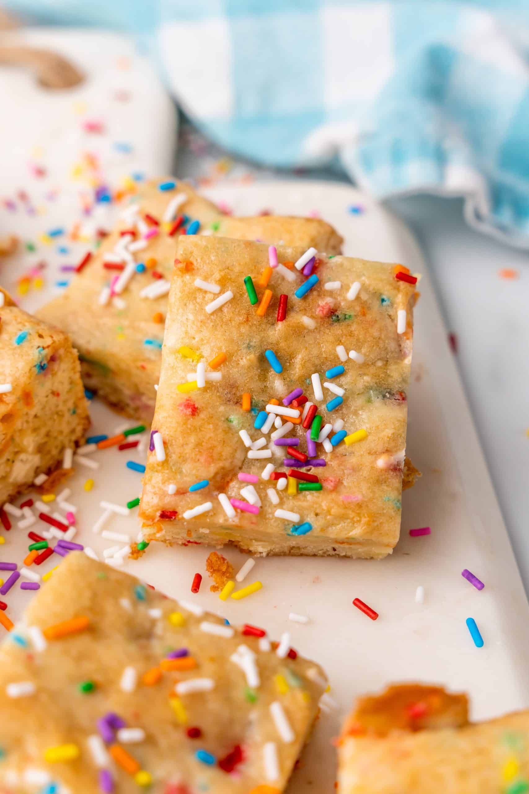 sprinkle topped birthday cake blondies on a white cutting board