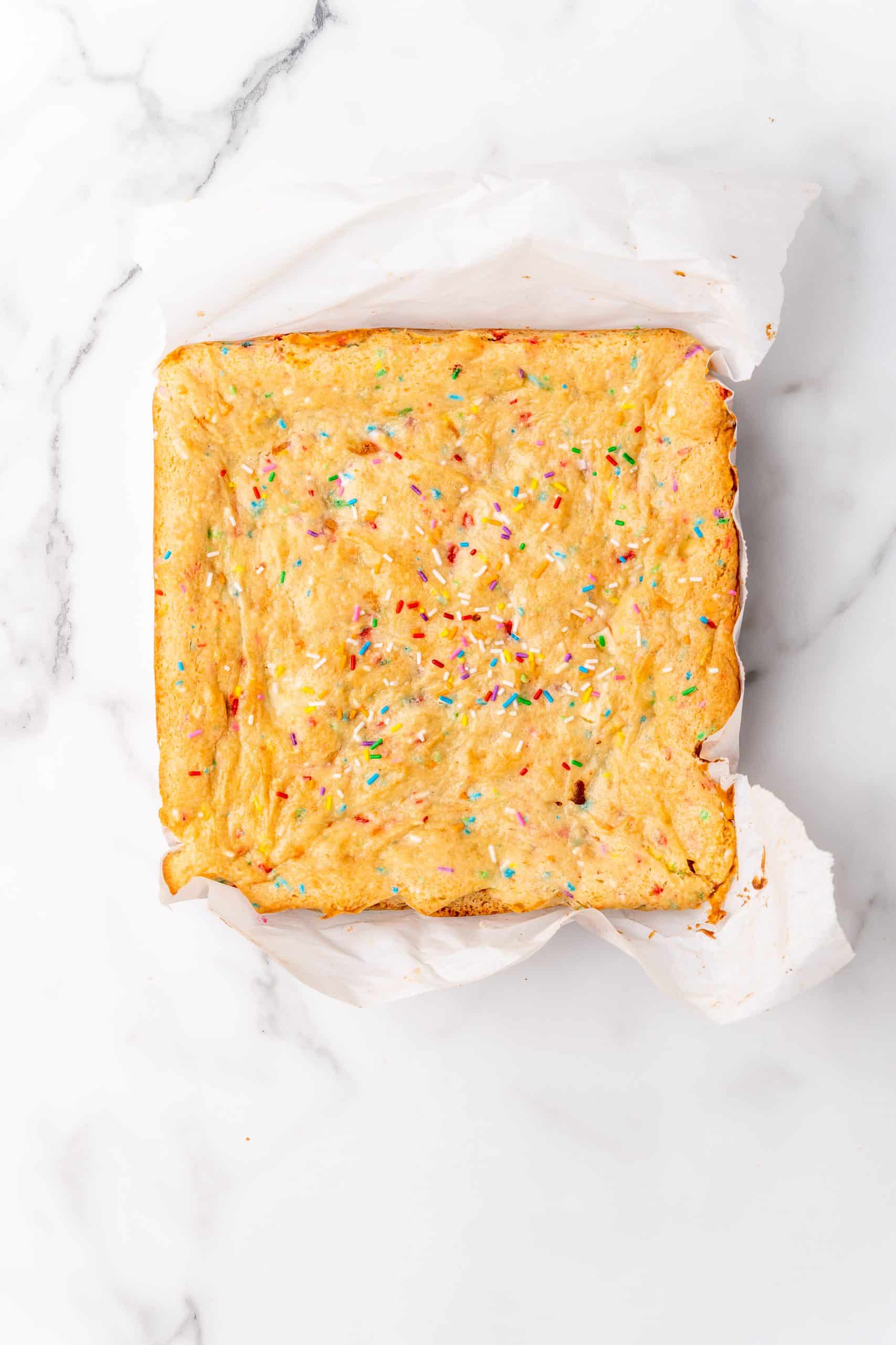 baked birthday cake blondies on crumpled parchment paper