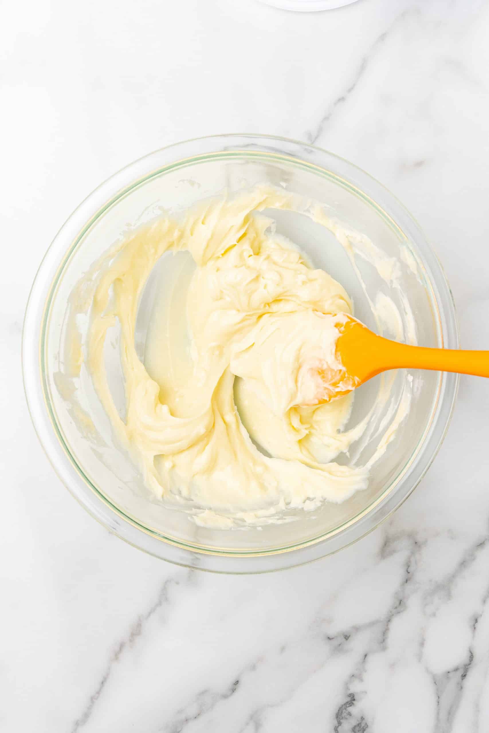 powdered sugar and cream cheese mixed together in a glass mixing bowl