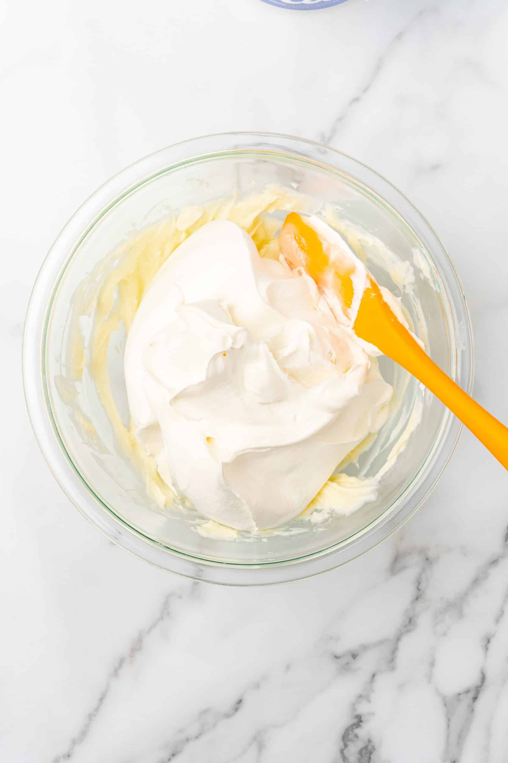 powdered sugar and cream cheese mixed together in a glass mixing bowl