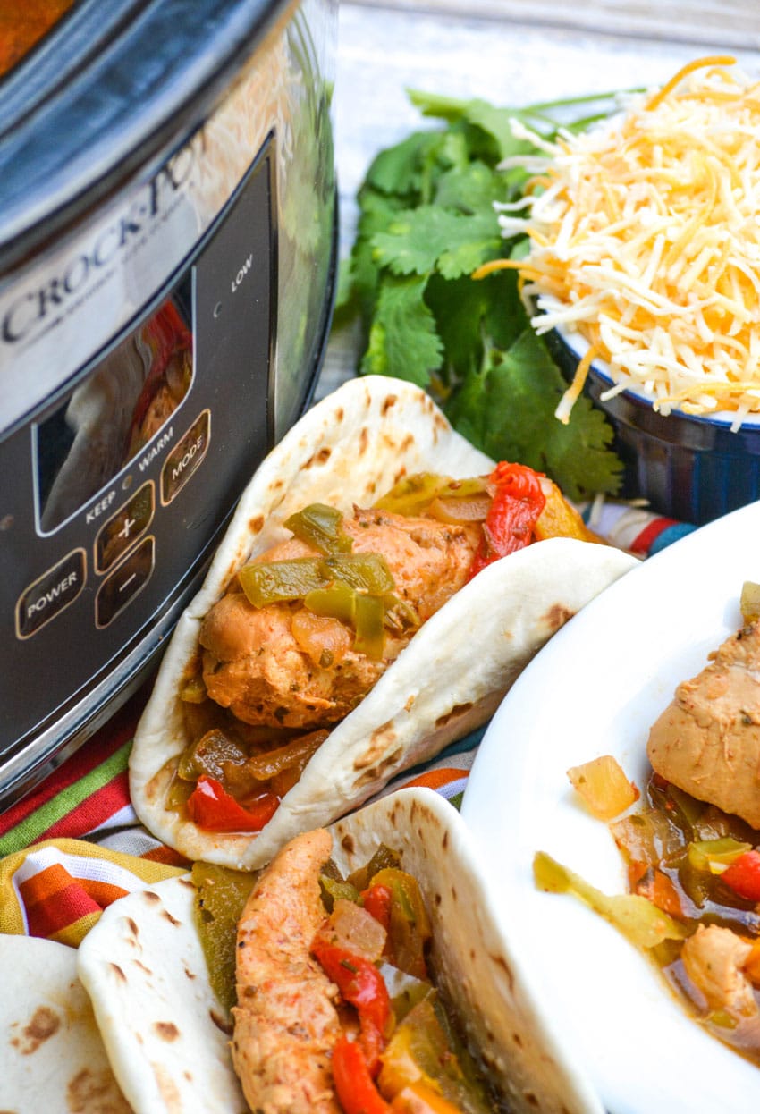 chicken fajitas in flour tortillas resting against a slow cooker
