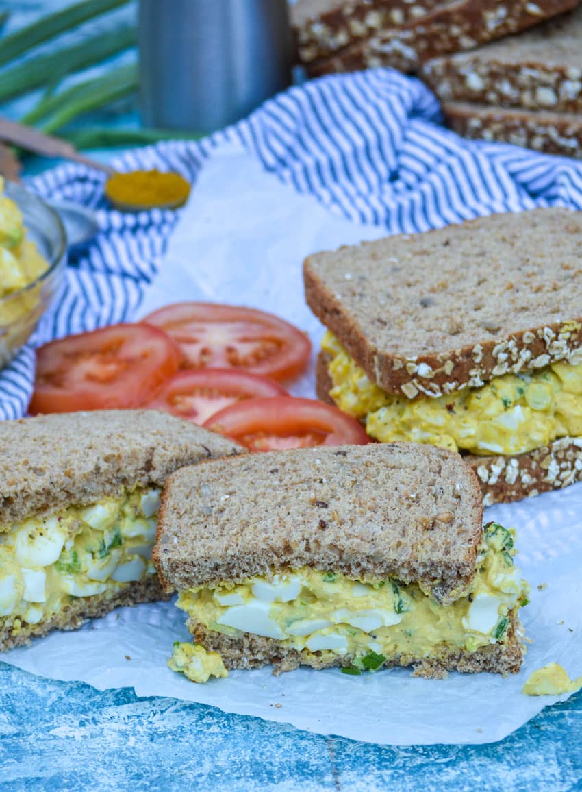 halves of curry egg salad sandwiches on white parchment paper