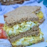 two stacked halves of curry egg salad sandwiches on white parchment paper