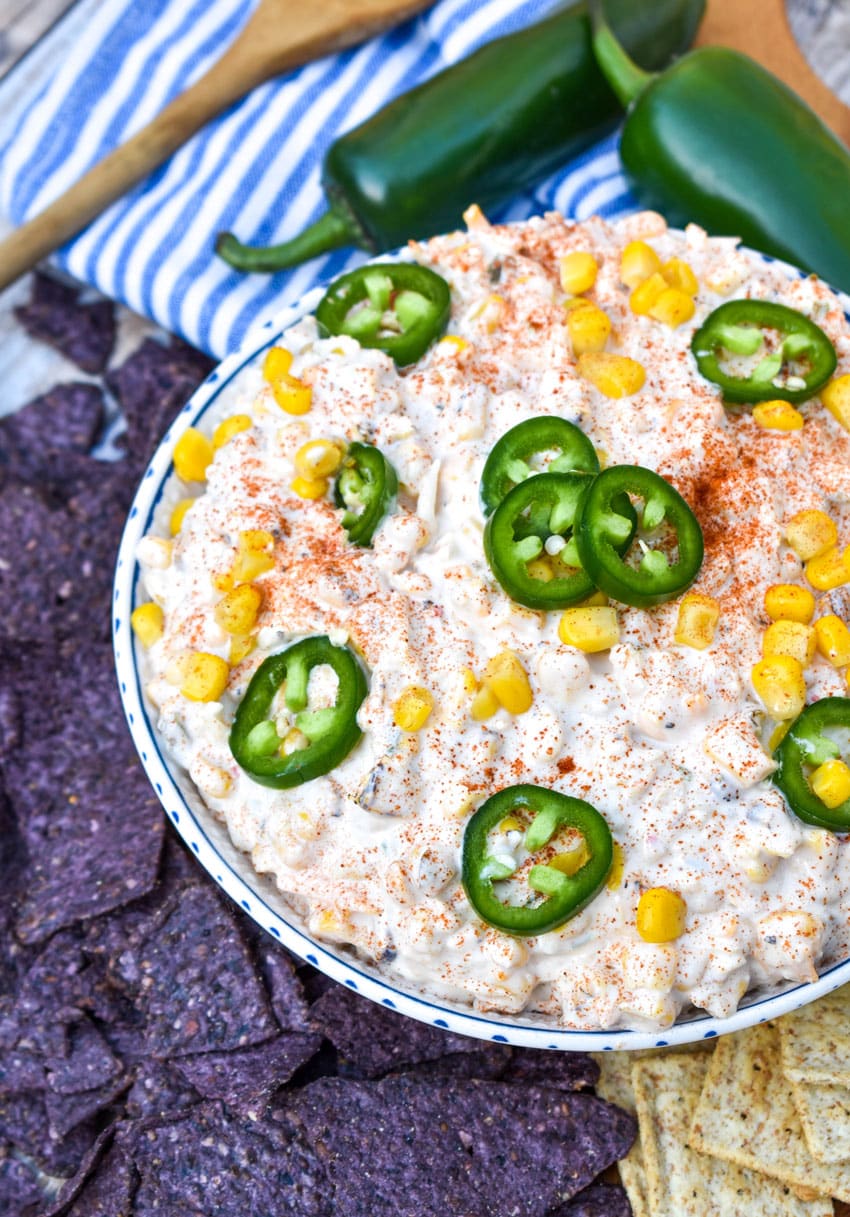elote corn dip in a white bowl surrounded by tortilla chips