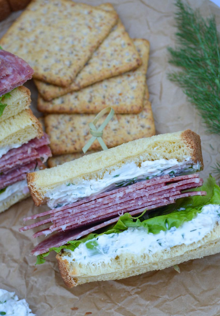 whipped cream cheese spread with herbs on a salami sandwich