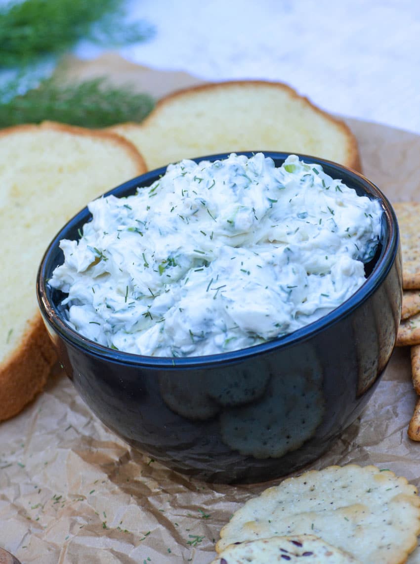 herbed cream cheese spread in a black bowl surrounded by crackers