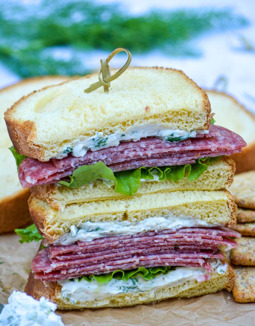 whipped cream cheese spread with herbs on a salami sandwich