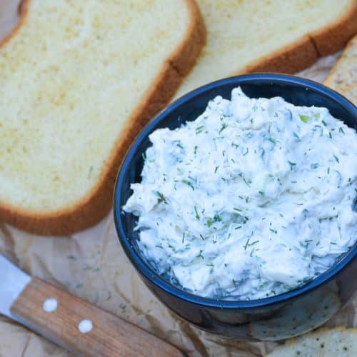 herbed cream cheese spread in a black bowl surrounded by crackers