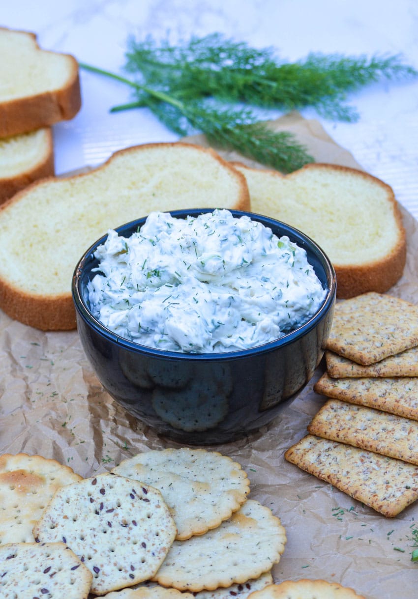 herbed cream cheese spread in a black bowl surrounded by crackers