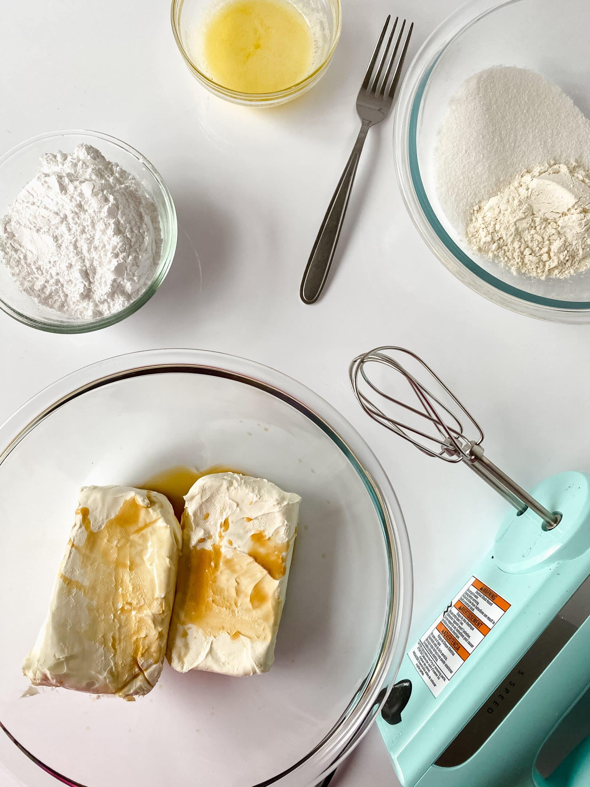 cream cheese mixture in a glass bowl next to a baking sheet topped with hollowed out danish
